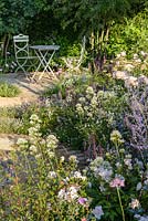 Rosa 'Wildeve', Centranthus and Salvia with table and chairs. 'Best of Both Worlds', RHS Hampton Flower Show 2018