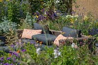 Outdoor Rattan sofa surrounded by raised bed with mixed perennial planting - RNIB's Community Garden, RHS Hampton Court Palace Flower Show 2018