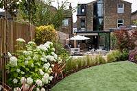 Looking towards house in garden with artificial lawn, including curved borders Contemporary garden in Dulwich 