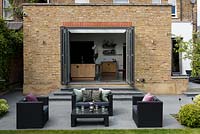 Lounge furniture on patio with view to house extension with bifold doors. 