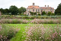 View across flowerbeds of Miscanthus sinensis 'Kleine Silberspinne' and Gaura lindheimeri 'Rosyjane' to house. Heale House, Middle Woodford, Salisbury, Wilts, UK. 