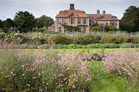 View across flowerbeds of Miscanthus sinensis 'Kleine Silberspinne' and Gaura lindheimeri 'Rosyjane' to house. Heale House, Middle Woodford, Salisbury, Wilts, UK.