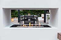 Modern London garden planted with lush foliage, view through fireplace