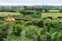 A exotic country garden with views to Hannington Hill  near Watership Down beyond. Exotic planting below includes Trachycarpus fortunei, Trachycarpus wagnerianus and Musa basjoo.