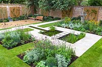View of pond and stepping stones, surrounded by mixed beds and Armillary Sundial in walled city garden. Garden design by Peter Reader Landscapes.
