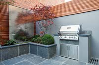 BBQ with Acer palmatum in raised integral bed with steel water wall, London