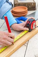 Using a tape measure to mark along piece of wood.