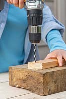 Using drill to make holes in wood.