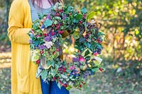 Woman holding up completed willow wreath in garden