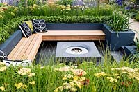 Modern seating area with fireplace surrounded by raised flower beds with 
Achillea, Agapanthus and Buxus sempervirens. 
Best of Both Worlds garden  
RHS Hampton Court Palace Flower Show 2018