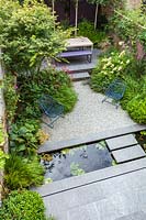 Overview of paved patio area with narrow garden pond. Garden designed by John Davies Landscape.