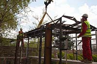 Parts of pavilion lowered into place by crane in preparation for RHS Chelsea Flower Show