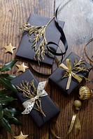 Christmas presents tied with gold ribbons and decorated with painted foliage