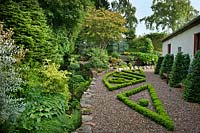 From left - Bert's Bank including Eleagnus 'Quicksilver' with Cornus - dogwood -
 behind, Weigela, Hostas and Heleniums by the stream. The boxwood Parterre, 
Acer micranthum by fruit cage, glasshouse above the Kitchen Garden, stable block
 with Yew buttreses to the right