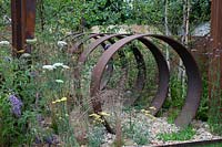 Detail of monolothic steel structures and wildflowers in Brownfield - Metamorphosis garden at Hampton Court Flower Show, London, 2017.