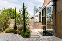 Contemporary house with circular stone sett driveway with multi-stemmed Betula utilis
 jacquemontii - Himalayan birch tree and pencil Cupressus in circular border 
with cedar batten fence 