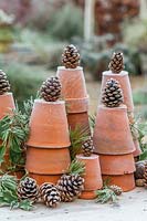 Festive display using stacked terracotta pots, pine and frosted pine cones. 