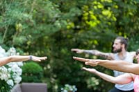People practicing yoga in garden.