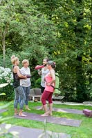 People talking after Yoga class in summer garden. 