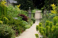Double border with Euphorbia either side of path leading to entrance gates