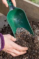 Woman adding horticultural grit to compost to make it free-draining.
