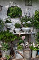 View of old facade with sewing table, mirror, plants in pots and metal pots