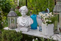 Vintage decorations with a bust of a woman, lanterns, potted plant and jug of honesty 