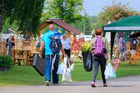 Members of the public laden with plants in carrier bags, walking down the main avenue at the RHS Malvern Spring Festival 2017.