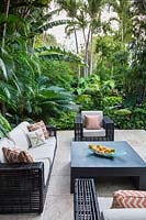 Modern seating area surrounded by lush tropical planting. Florida, USA. Garden design by Craig Reynolds Landscape Architecture.
