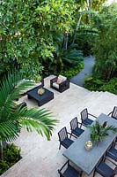 View across tropical, multi-level garden with modern furniture. Florida, USA. Garden design by Craig Reynolds Landscape Architecture.