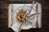 Overhead view of dried Hydrangea place setting on vintage book charger