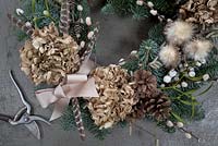 Close up of wreath with dried Hydrangea flower, pine cones, mistletoe, 
snowberries, pussy willow, pheasant feathers and seed heads