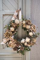 Natural wreath with Hydrangea, fir and feathers, hanging on cupboard door