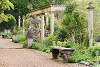 Great Terrace with colonnade, herbaceous border, raked gravel and statuary at Iford Manor, Bradford-on-Avon, Wiltshire, UK. 