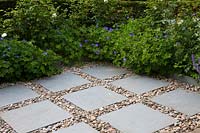 Paving squares set in pebbles edged in geraniums
