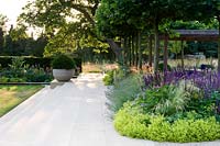 Flowering, herbaceous borders spill onto paved terrace and steps. 