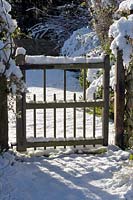 Garden gate in the snow at Burrow Farm Garden, Dalwood, Devon, UK.
