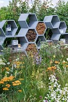A wall made from honeycomb shapes containing twigs to encourage solitary bees, surrounded by nectar-rich flowers. The Urban Pollinator Garden, Designed by Caitlin McLaughlin. RHS Hampton Court Palace Garden Festival, 2019. 
