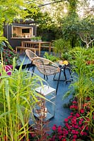 Outdoor kichen and seating area surrounded by tender plants. B and Q Bursting Busy Lizzie Garden at RHS Hampton Court Palace Garden Festival Show 2018