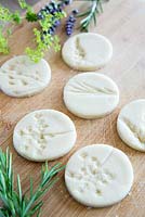 Circular salt dough discs with impressions left by flowers to create gift tags