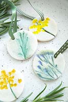 Gift tags on ribbons made with salt dough and decorated with pressed and painted flowers 