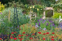 Miserden Park, Gloucestershire, summer, with spectacular views over a deer park and rolling Cotswold hills beyond. The large double borders overflowing with summer planting.