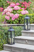 Steps with lanterns and retaining wall between levels in modern suburban garden