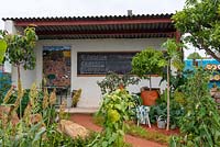 Shelter with blackboard for teaching, edibles in the front garden - The Camfed Garden: Giving Girls in Africa a Space to Grow, RHS Chelsea Flower Show 2019.