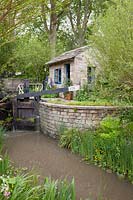 The Welcome to Yorkshire Garden. View of the lock and keeper's office with canal and water's edge planting which includes: Caltha palustris - Marsh Marigold and Iris pseudacorus. Sponsor: Welcome to Yorkshire