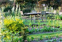 Dining area in the vegetable garden with lichen encrusted table and chairs at Sea View, Cornwall, UK in June.