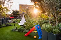 View across the garden with artificial grass, the slide and cacoon hanging tent. 