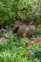 Woven willow seat, surrounded by Aquilegia, Alchemilla, Primula and a beech tree in the Breast Cancer Haven Garden - Chelsea Flower Show 2015 - Sponsor: Nelsons - Best Artisan Garden