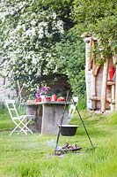 Rustic wooden table and chairs, table set for breakfast - fire place with cooking facilities in background.