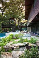 Garden enclosed by house with specimen tree, swimming pool, outdoor seating and rock garden